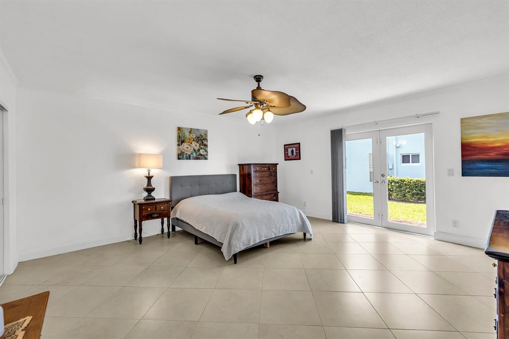 2835 Northeast 28th Avenue, Unit 3 Lighthouse Point, FL 33064 - Photo 18 of 30 a spacious bedroom with a bed and a chandelier