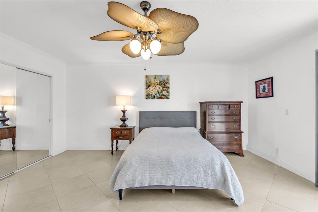 2835 Northeast 28th Avenue, Unit 3 Lighthouse Point, FL 33064 - Photo 19 of 30 a bedroom with a bed and a chandelier