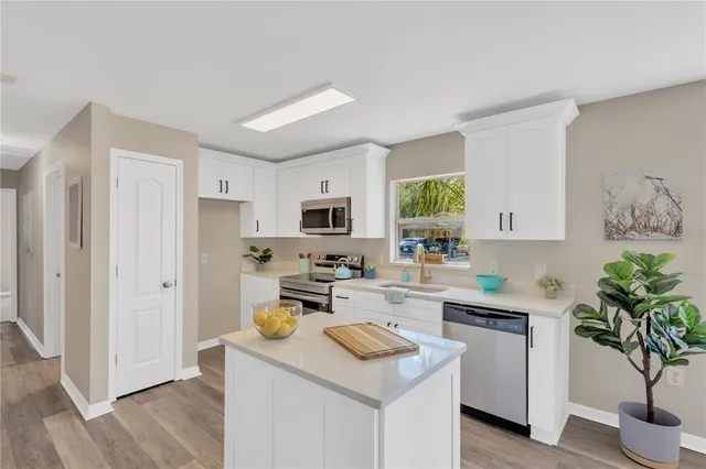 a kitchen with stainless steel appliances a stove a sink a refrigerator a white cabinets and wooden floor