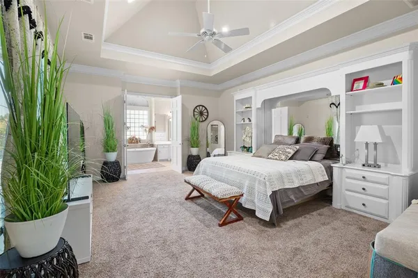 a spacious bedroom with a bed a mirror and a potted plant