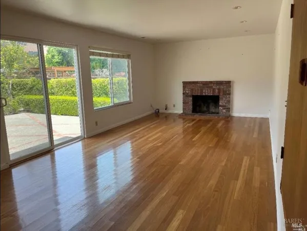 a view of empty room with wooden floor and fireplace