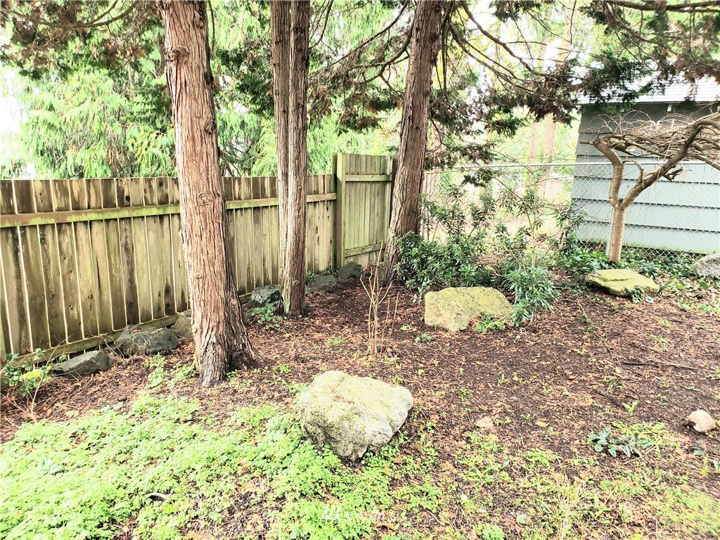8690 Illahee Road Northeast Bremerton, WA 98311 - Photo 15 of 40 a backyard of a house with table and chairs and wooden fence