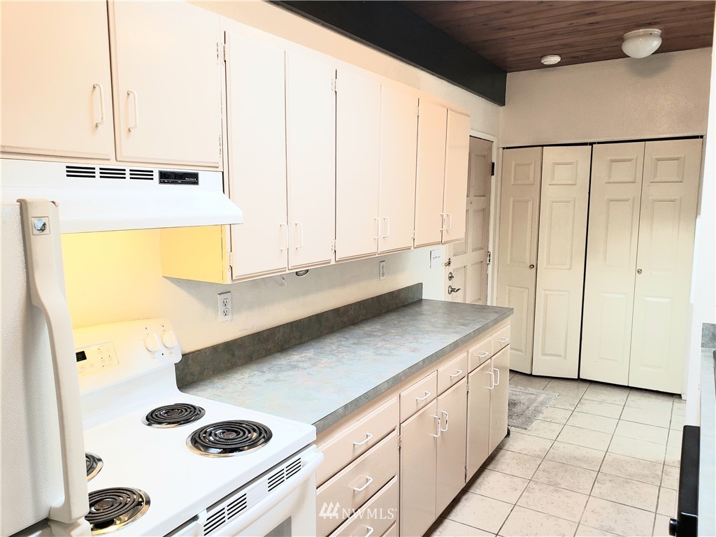 8690 Illahee Road Northeast Bremerton, WA 98311 - Photo 23 of 40 a kitchen with a sink a stove and white cabinets