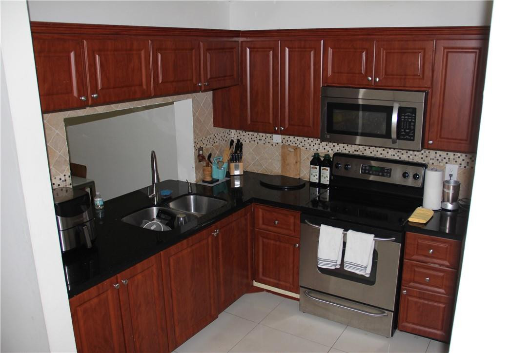 10932 West Sample Road, Unit F2 Coral Springs, FL 33065 - Photo 22 of 23 a kitchen with granite countertop stainless steel appliances and wooden cabinets