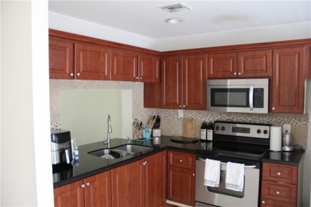 10932 West Sample Road, Unit F2 Coral Springs, FL 33065 - Photo 23 of 23 a kitchen with stainless steel appliances granite countertop a stove top oven a sink dishwasher and cabinets with wooden floor