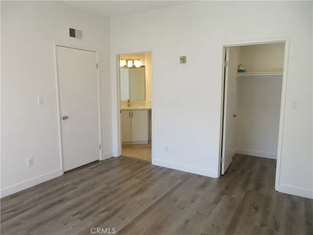 an empty room with wooden floor & closet area