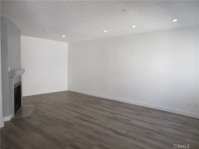 a view of an empty room with wooden floor and a fireplace