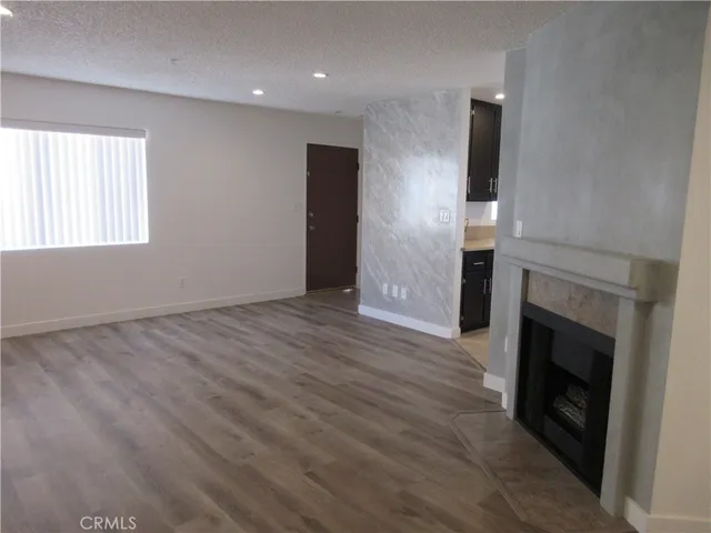 an empty room with wooden floor fireplace and windows