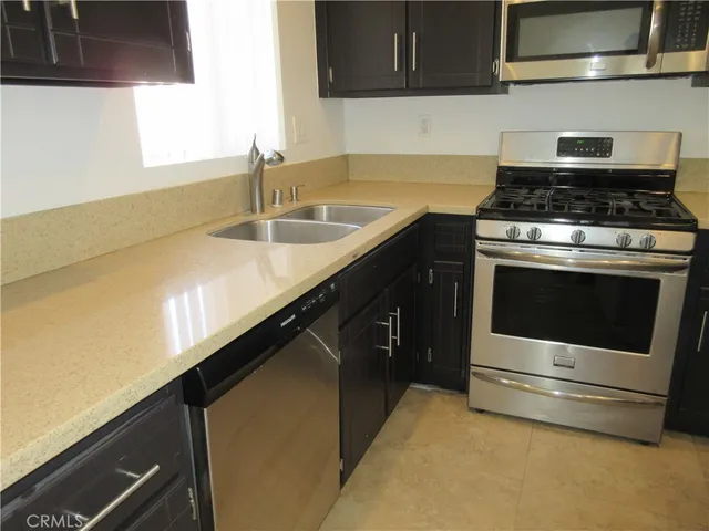 a kitchen with granite countertop a sink stainless steel appliances and cabinets