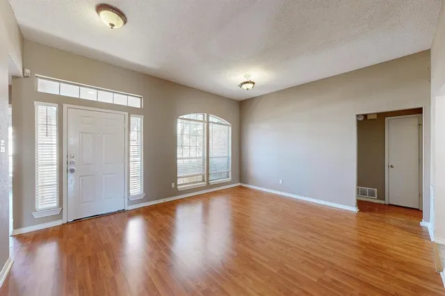 a view of an empty room with wooden floor and windows