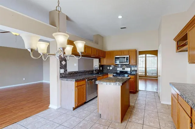 a kitchen with stainless steel appliances granite countertop a sink a stove and a refrigerator