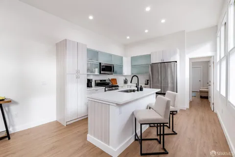 a kitchen with stainless steel appliances a stove a refrigerator a sink dishwasher and a refrigerator with wooden floor