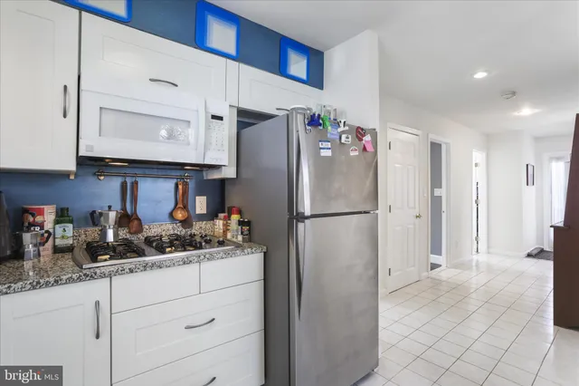 a kitchen with refrigerator a microwave a stove and white cabinets