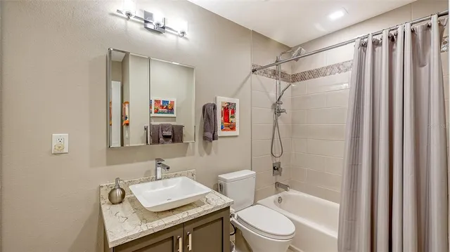 a bathroom with a granite countertop sink toilet and shower