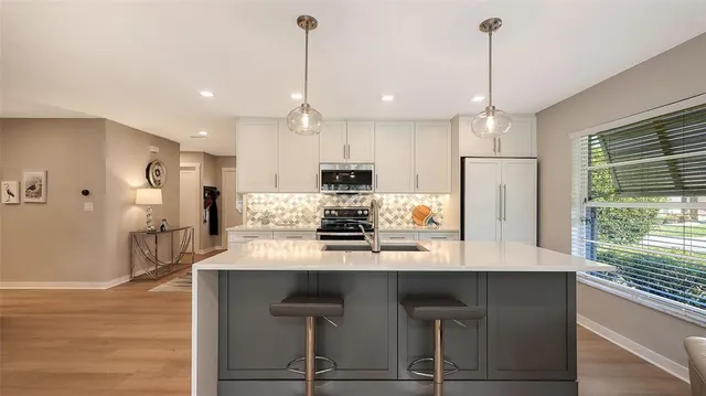 a kitchen with kitchen island a refrigerator a stove a center island a stove and a wooden floor