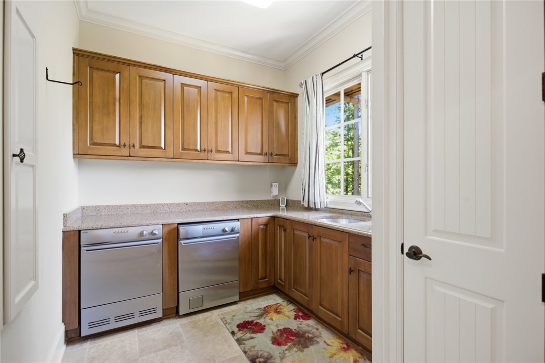 130 River Ridge Road Sunset, SC 29685 - Photo 19 of 47 This functional laundry room features ample cabinetry, a utility sink, and dual laundry appliances under a window overlooking green foliage.