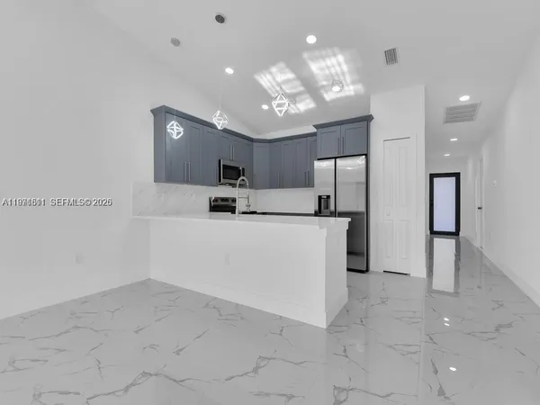 a view of kitchen with cabinets microwave and refrigerator