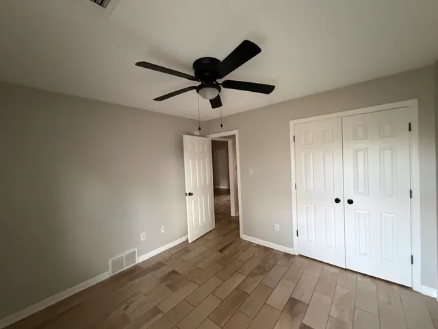 a view of empty room with wooden floor and ceiling fan