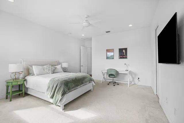 a spacious bedroom with a bed and a flat screen tv