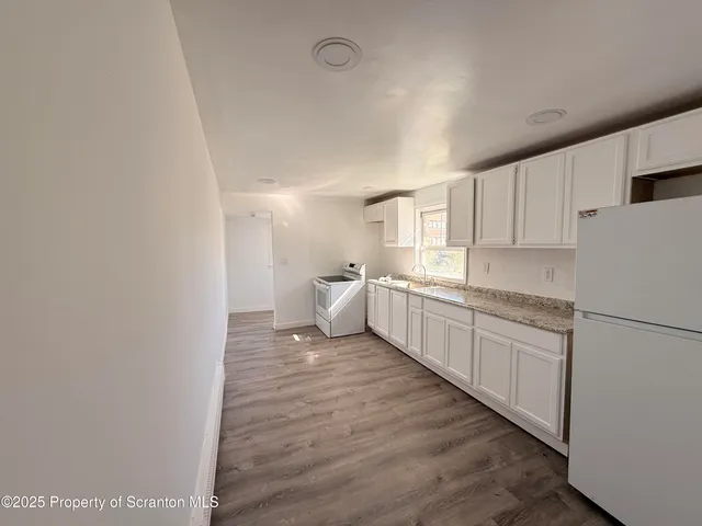 a large white kitchen with sink refrigerator and cabinets