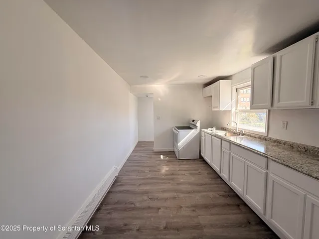 a view of a kitchen with a sink and wooden floor