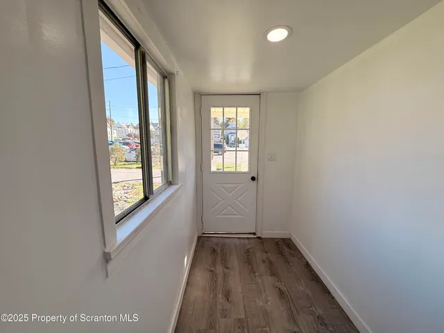 a view of hallway with window and wooden floor