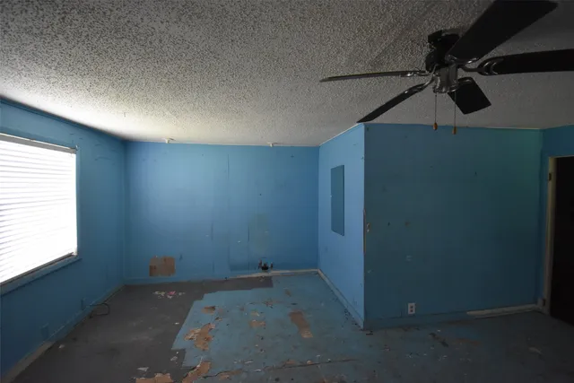 an empty room with a ceiling fan and a window