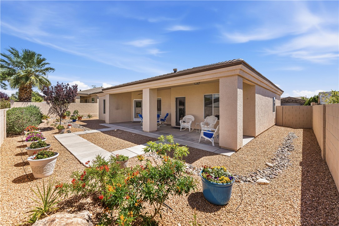 3315 Rainbow Mine Road Kingman, AZ 86401 - Photo 46 of 54 The property features a covered patio area with a stucco exterior, overlooking a landscaped yard with decorative gravel, mature plants, and a paved walkway