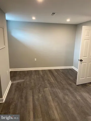 an empty room with wooden floor and white wall