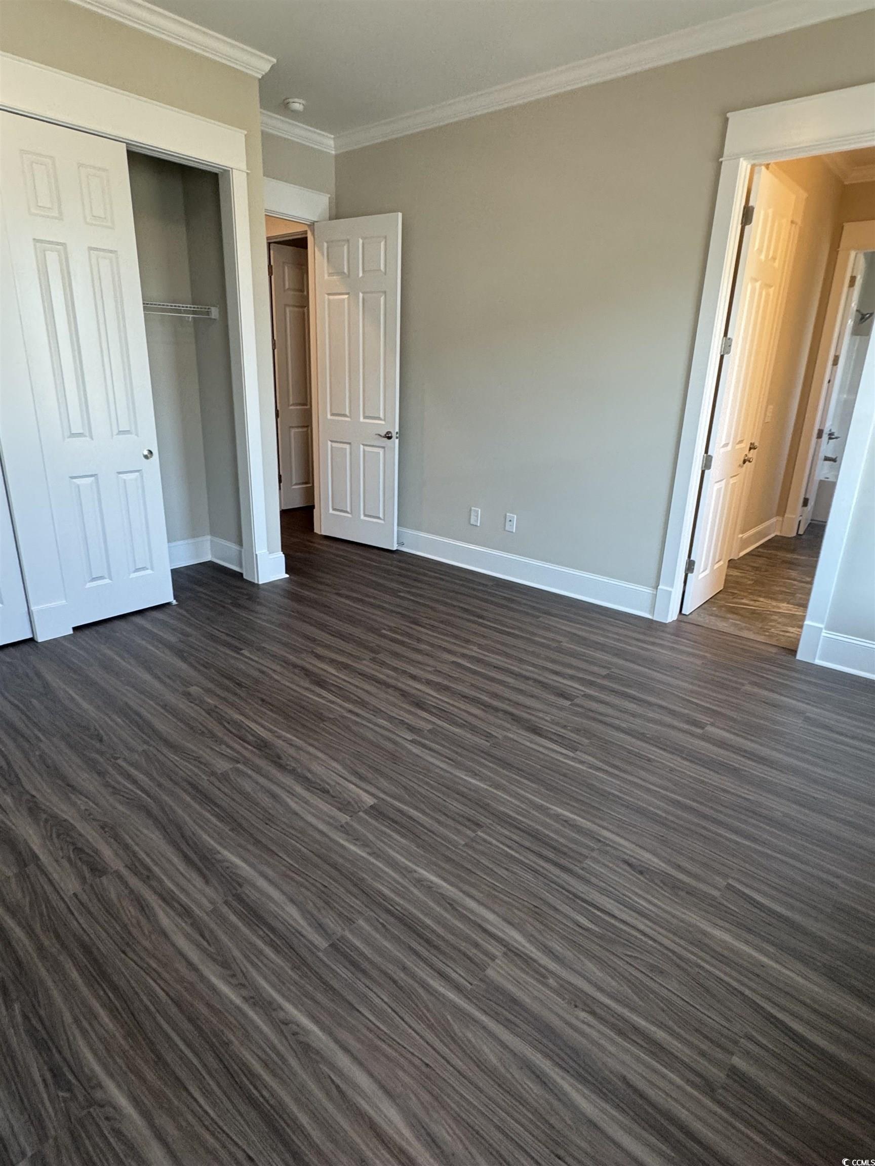 852 Iris Street, Unit D Myrtle Beach, SC 29577 - Photo 19 of 36 Unfurnished bedroom featuring ornamental molding, dark wood finished floors, and a closet