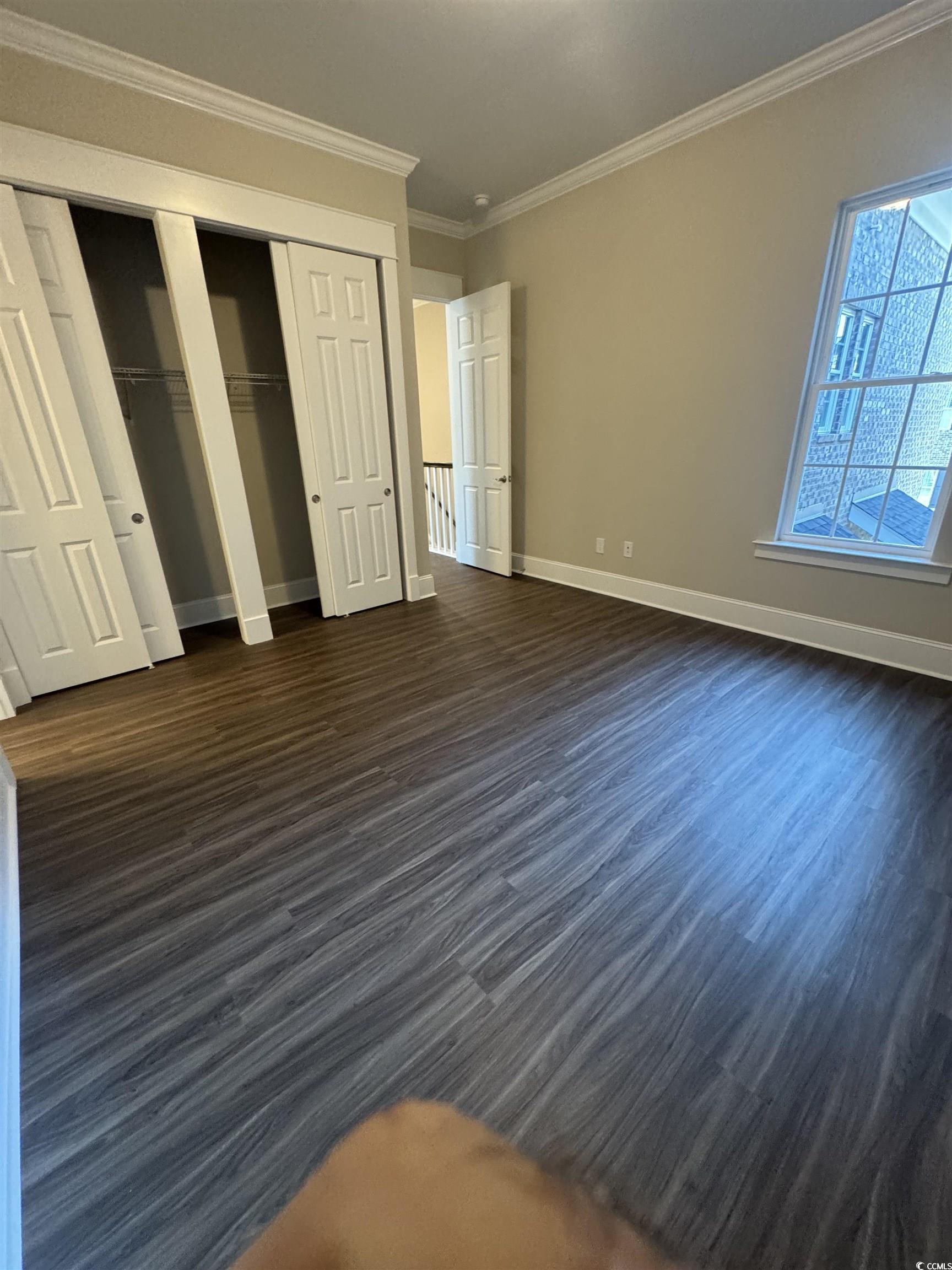 852 Iris Street, Unit D Myrtle Beach, SC 29577 - Photo 21 of 36 Unfurnished bedroom featuring dark wood finished floors, ornamental molding, and multiple closets
