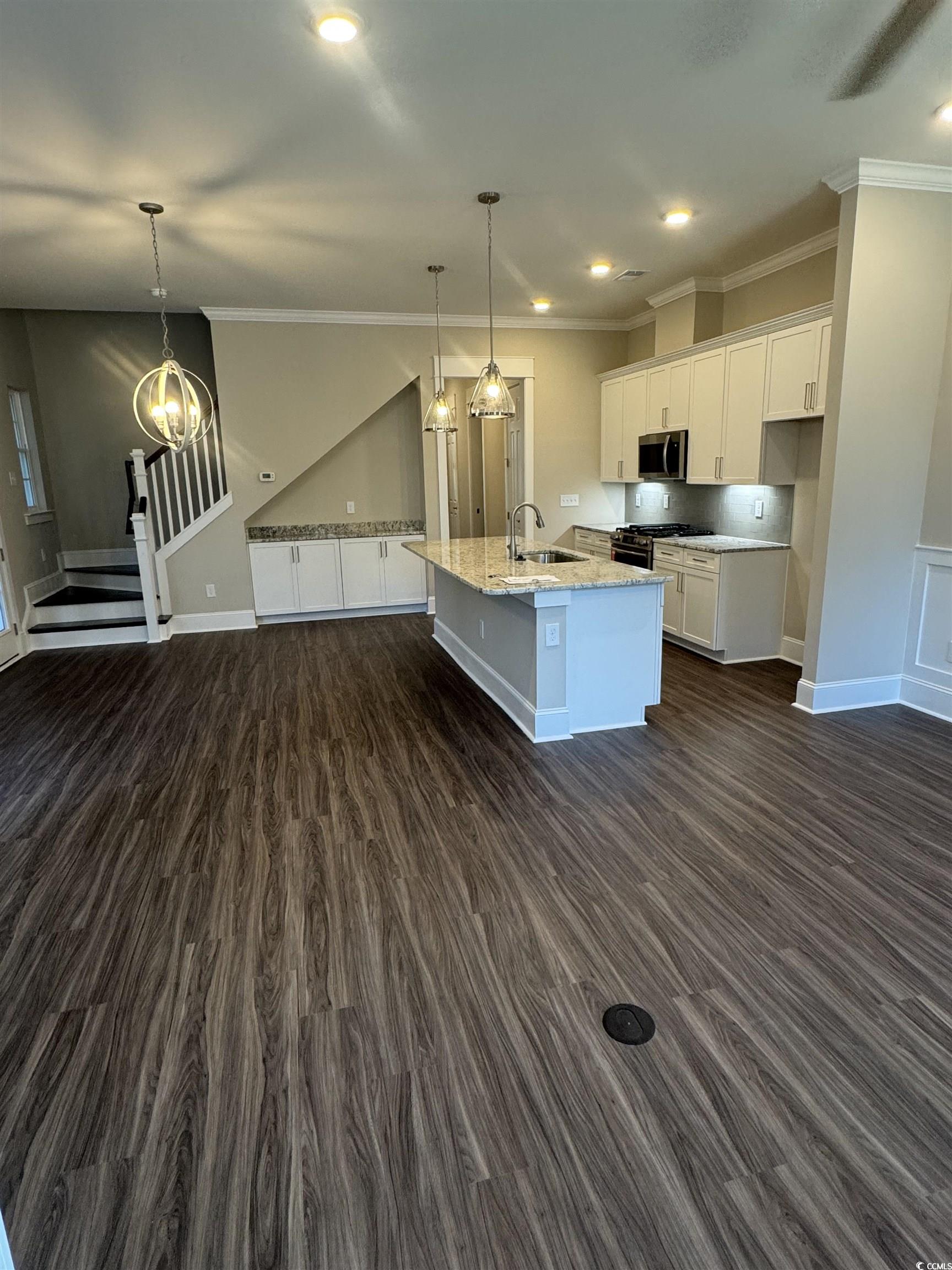 852 Iris Street, Unit D Myrtle Beach, SC 29577 - Photo 4 of 36 Kitchen with stainless steel appliances, dark wood-type flooring, white cabinetry, ornamental molding, and a kitchen island with sink