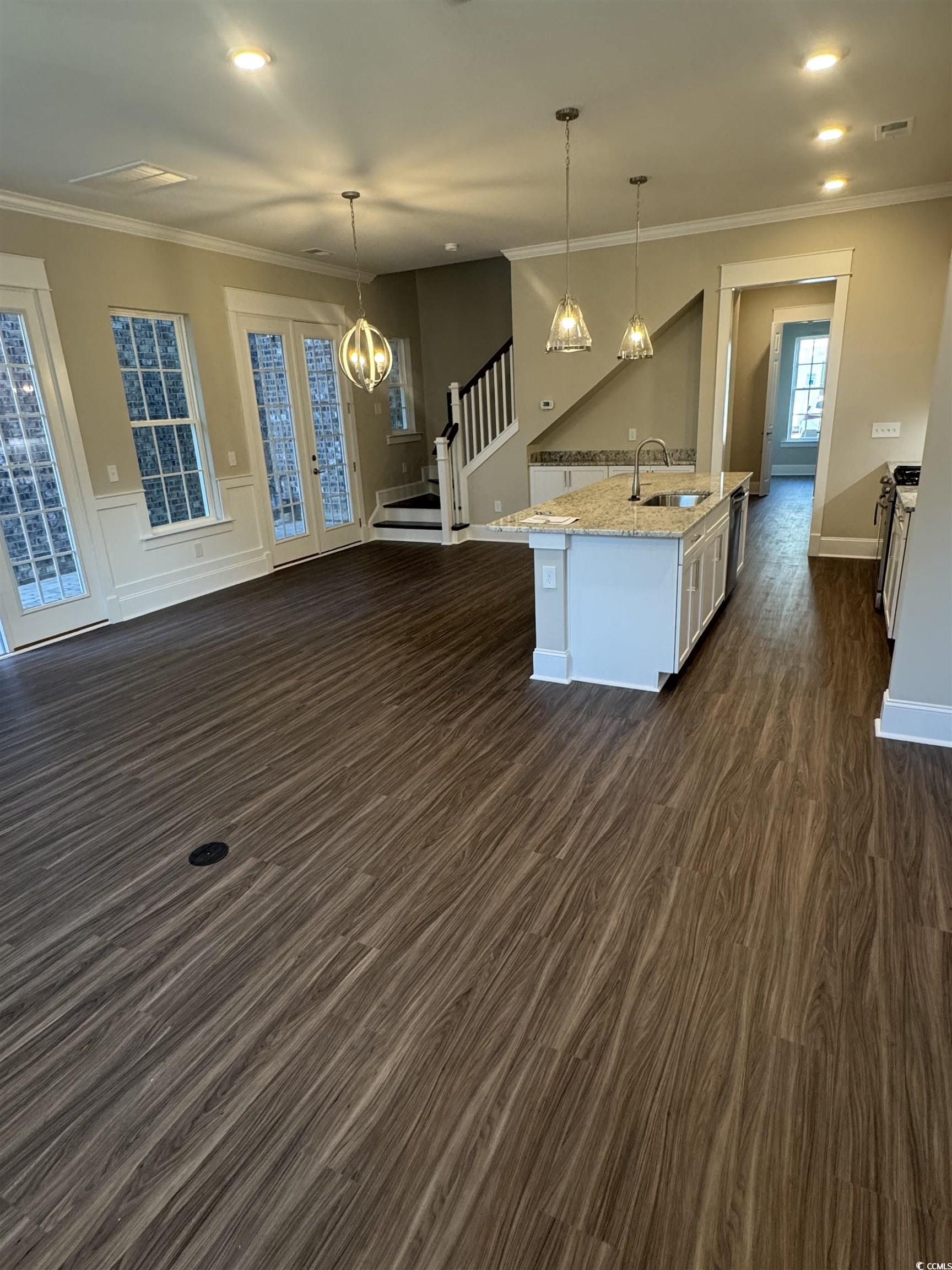 852 Iris Street, Unit D Myrtle Beach, SC 29577 - Photo 5 of 36 Kitchen featuring dark wood finished floors, light stone counters, decorative light fixtures, a center island with sink, and ornamental molding
