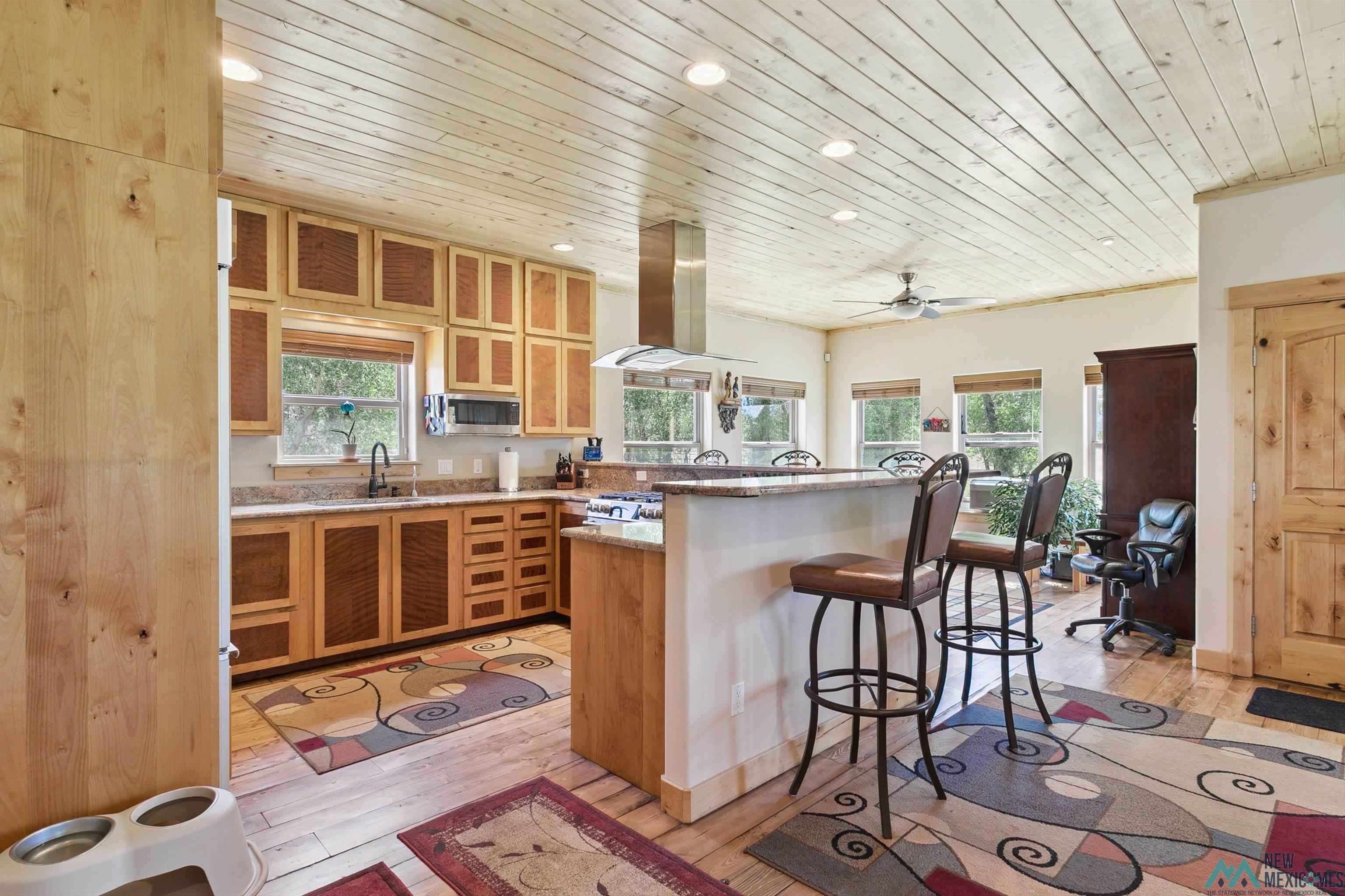 31 Cr 343 Road Chama, NM 87520 - Photo 11 of 44 Kitchen with glass insert cabinets, a breakfast bar, wood ceiling, recessed lighting, and range hood