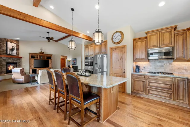 a large kitchen with stainless steel appliances granite countertop a stove a sink dishwasher and white cabinets with wooden floor
