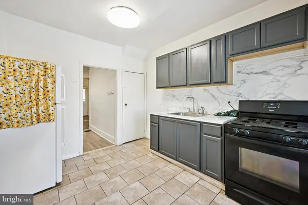 a kitchen with granite countertop a stove top oven cabinetry a sink and a refrigerator