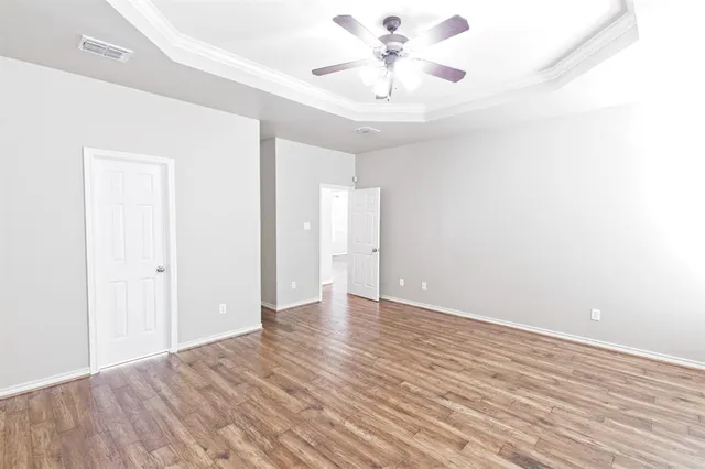 an empty room with wooden floor and ceiling fan