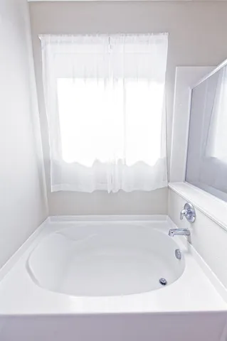 a white bath tub sitting in a bathroom next to a window
