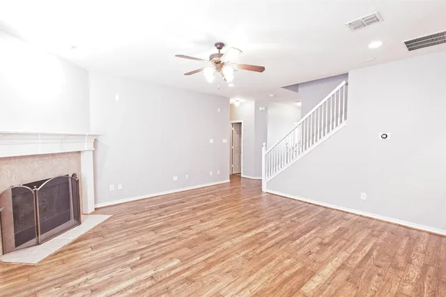 a view of an empty room with wooden floor and a fireplace