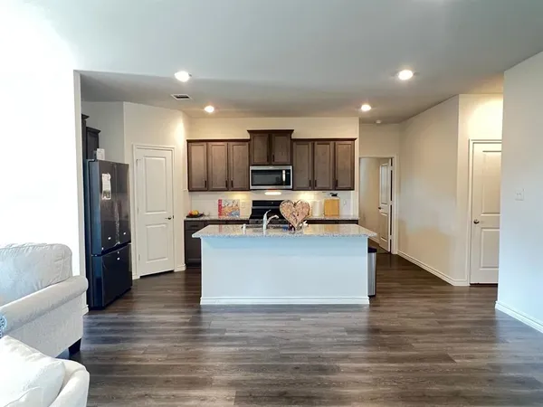 a view of kitchen with kitchen island stainless steel appliances refrigerator stove microwave and cabinets