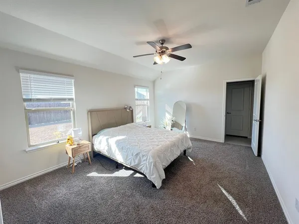a bedroom with a bed ceiling fan and a window