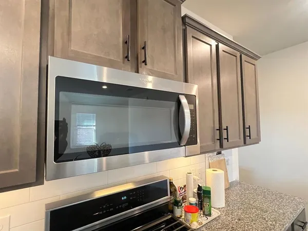 a hallway with granite countertop a stove and a microwave