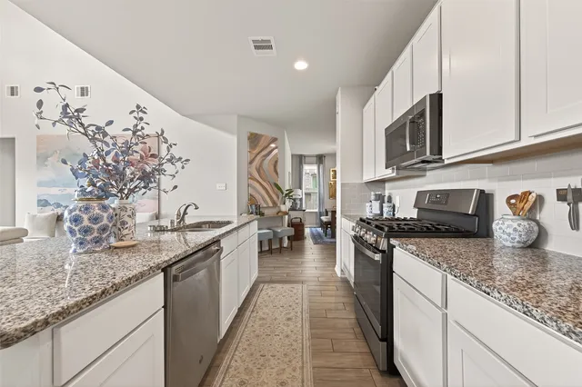 a kitchen with granite countertop stainless steel appliances stove top oven and cabinets