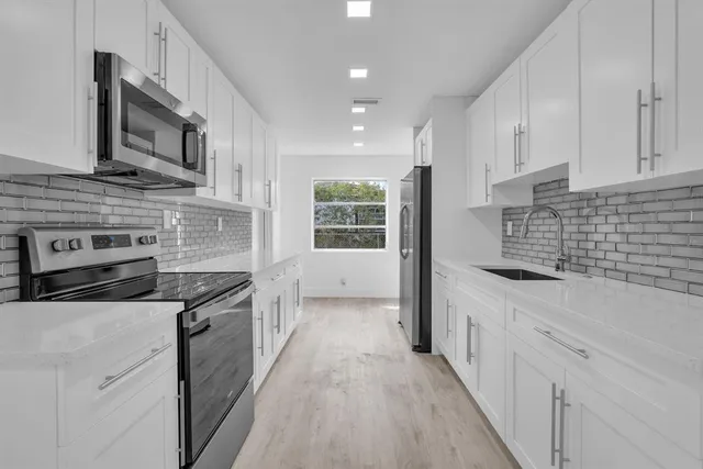 a kitchen with stainless steel appliances granite countertop a stove a sink and a microwave