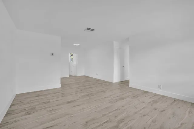 a view of empty room with wooden floor and windows