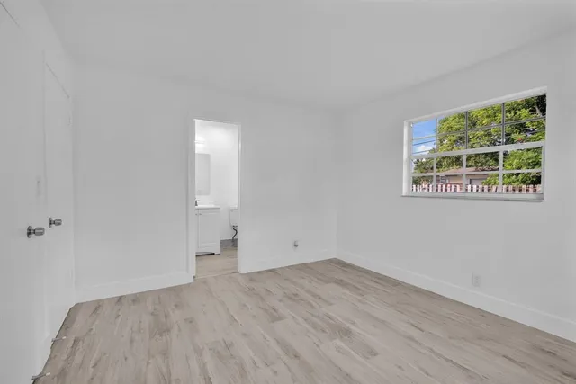 a view of a room that has wooden floor and a window