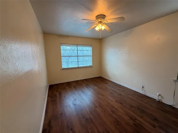 an empty room with wooden floor chandelier and windows