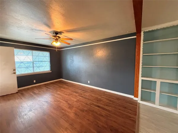 a view of an empty room with a window and wooden floor