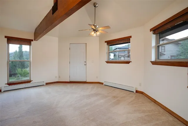 an empty room with windows and ceiling fan