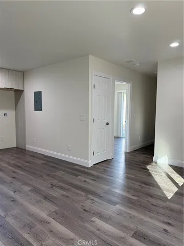 a view of an empty room with wooden floor and closet